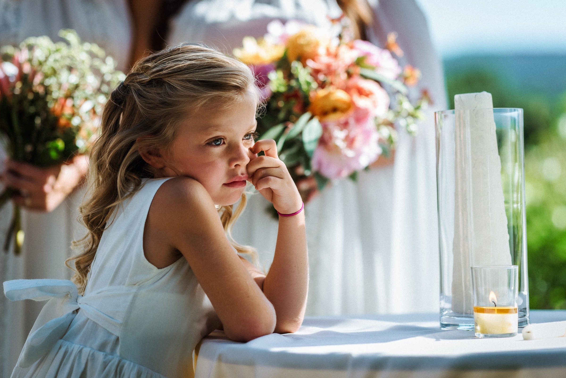 Flower girl resting at the ceremony table beside a candle