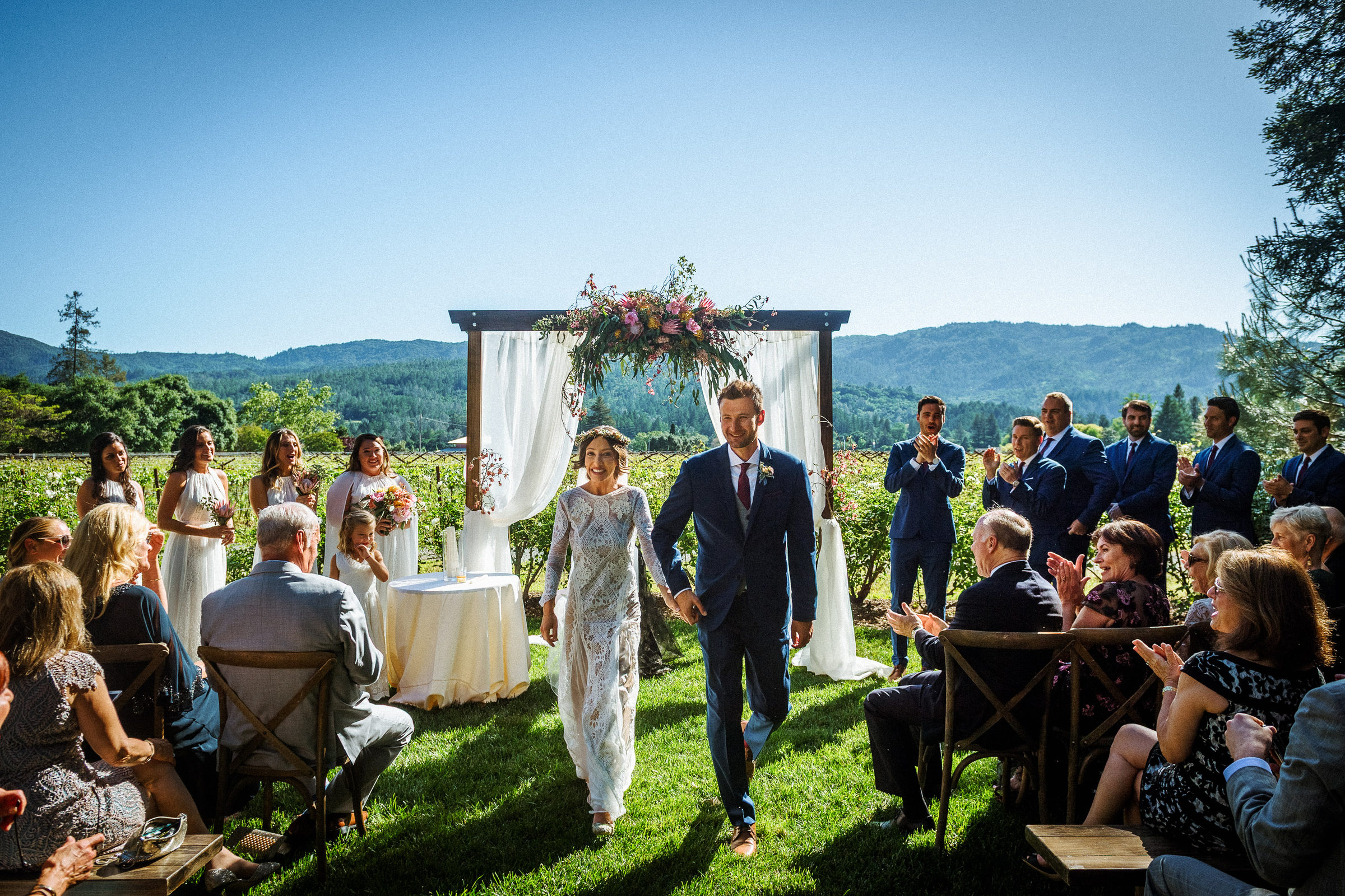 Bride and groom recessing down the aisle with the Napa vineyards behind them