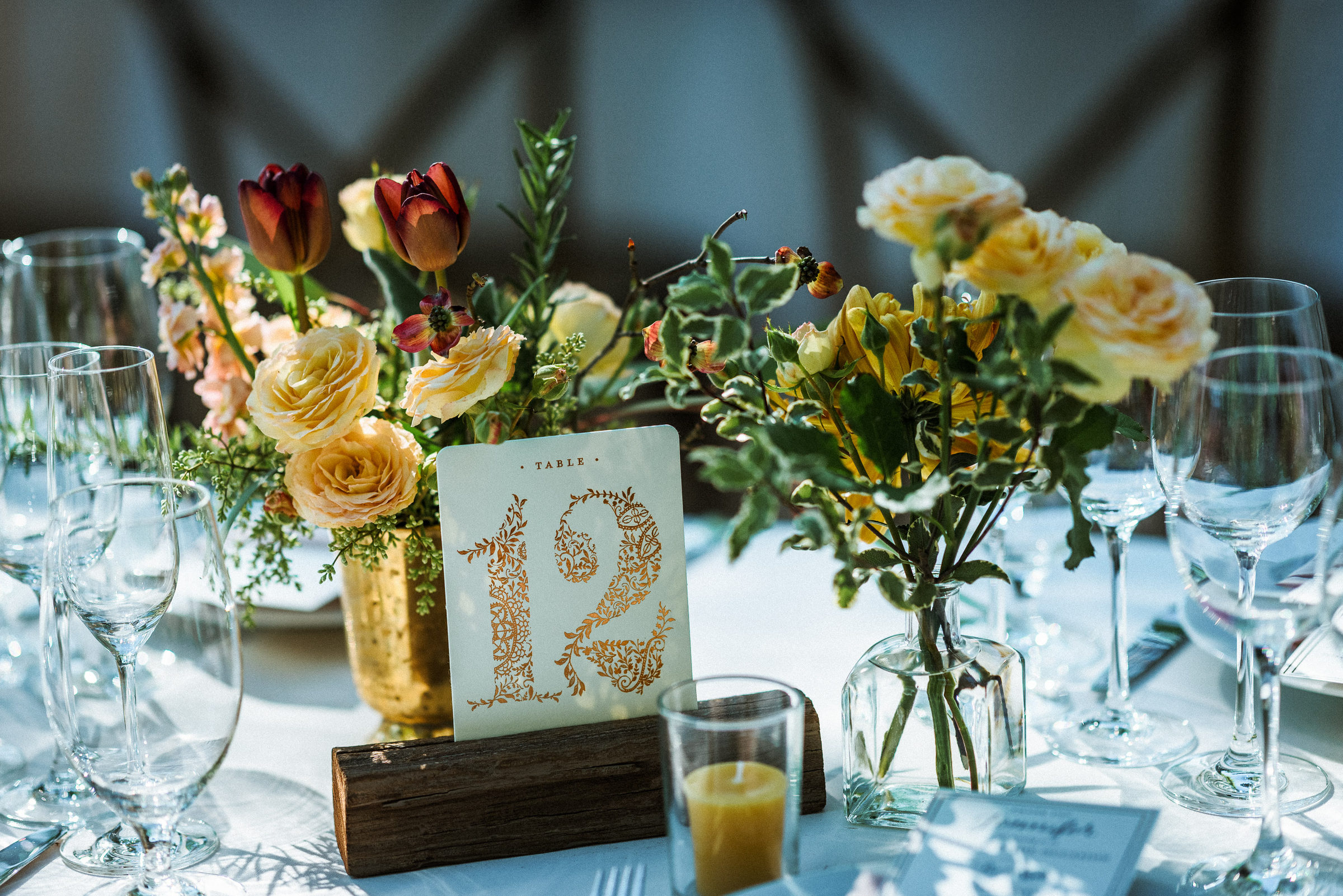 Gilded table number framed by tulips and garden roses