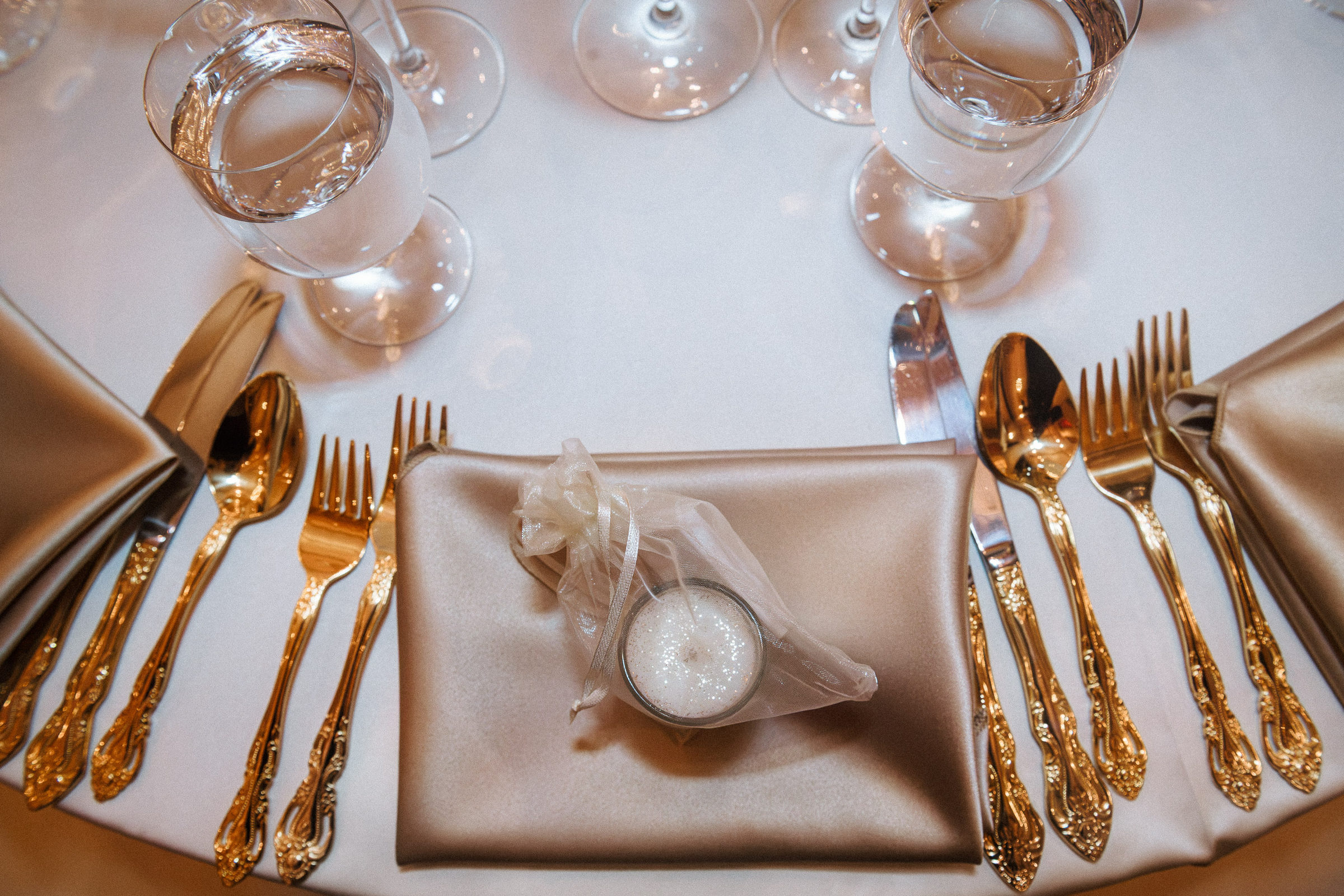 Gold flatware and a candle favour set at each place