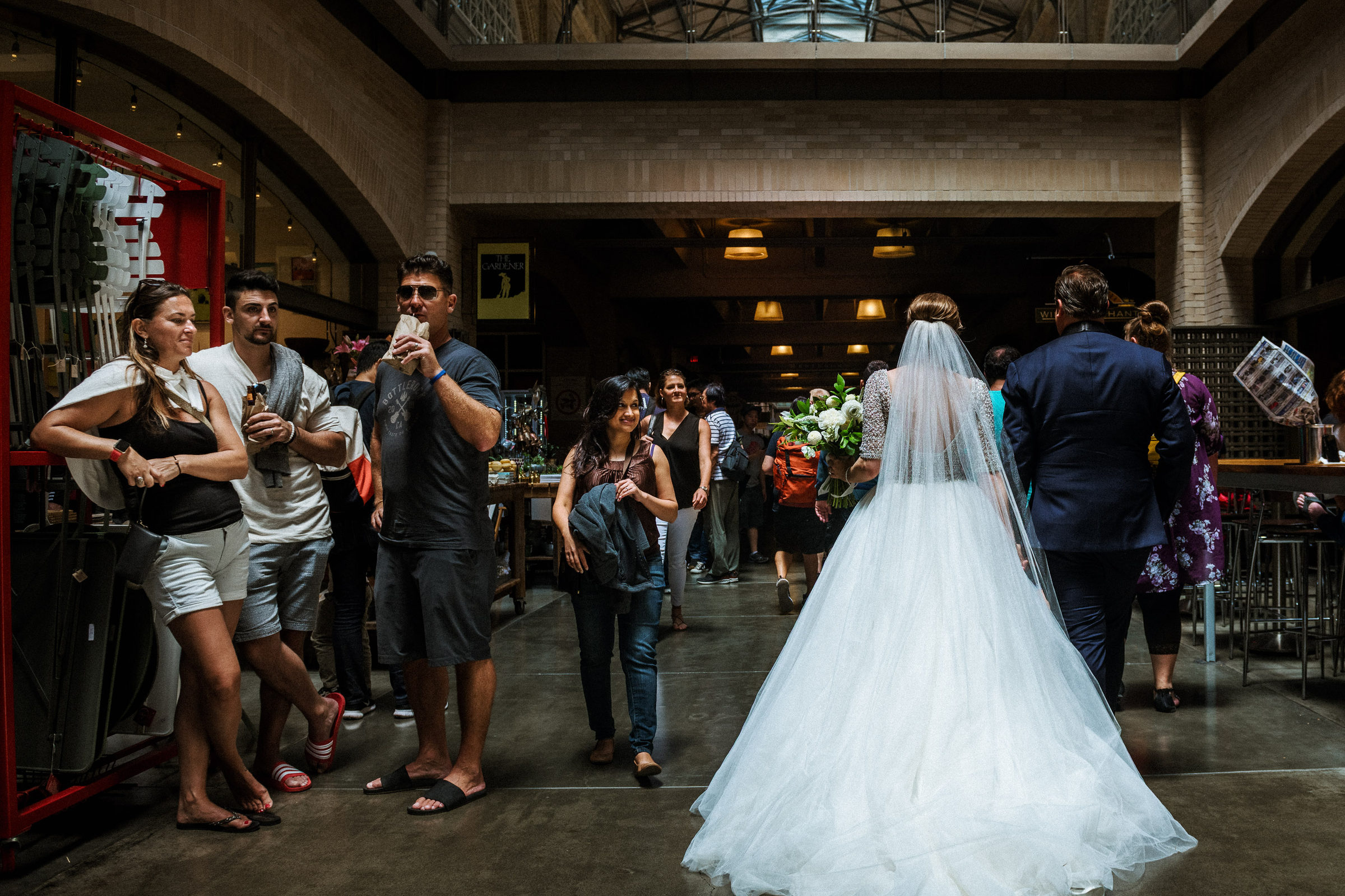 Bride crossing the Ferry Building hall with her veil trailing behind her