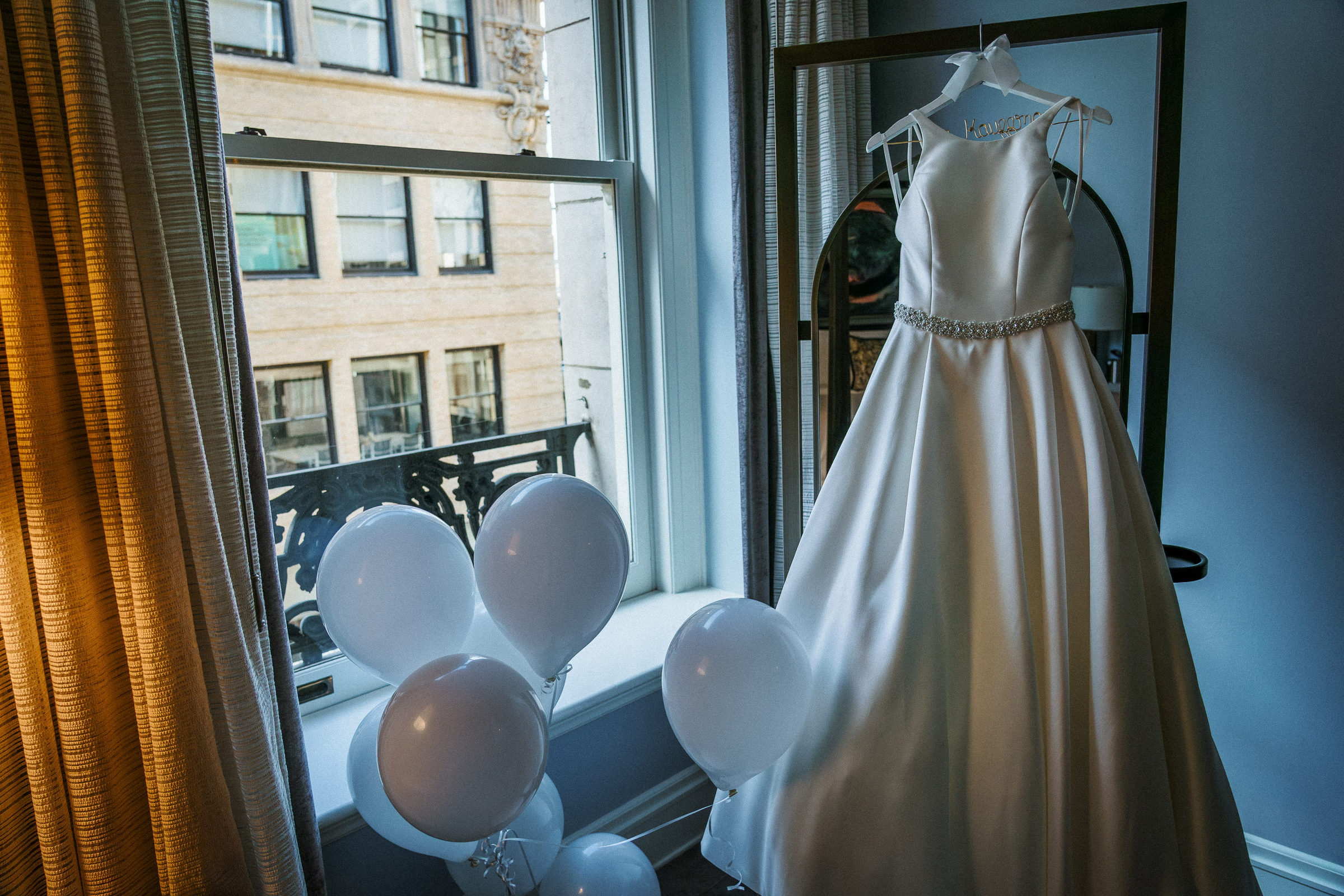 Wedding gown hanging by a hotel window above downtown San Francisco