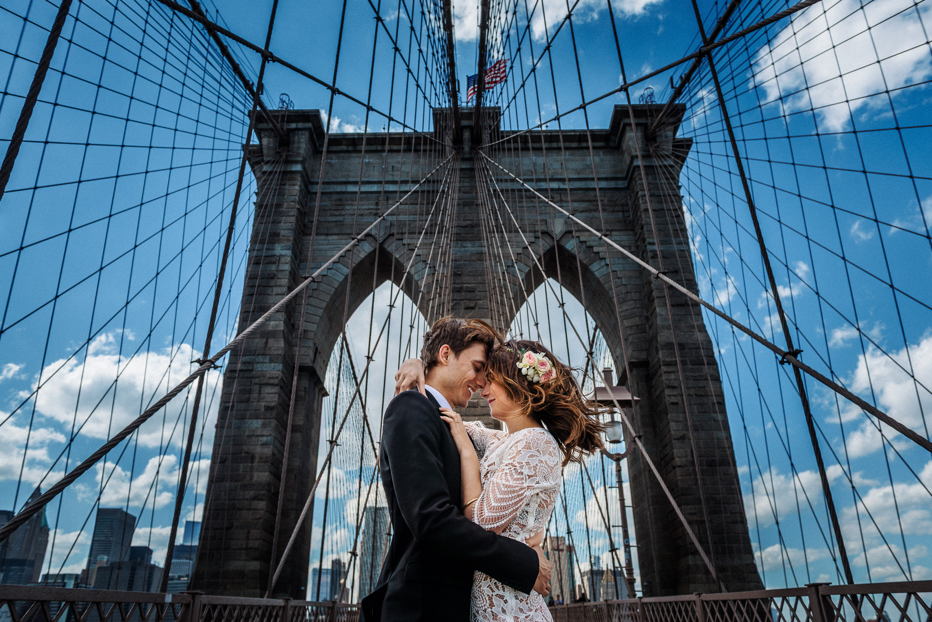 Bride and groom embracing beneath the Brooklyn Bridge in New York City