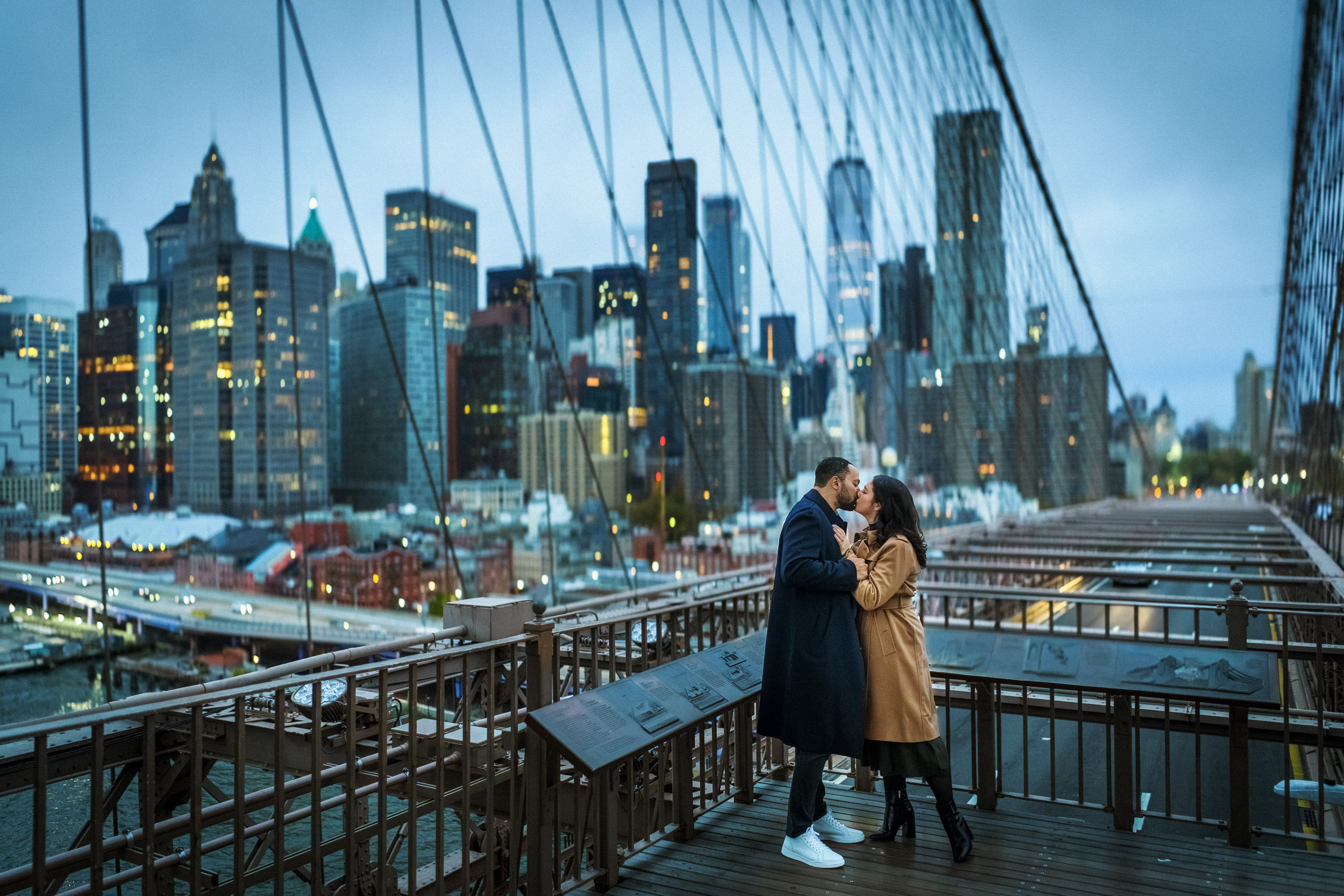Engaged couple overlooking the Manhattan skyline from the Brooklyn Bridge