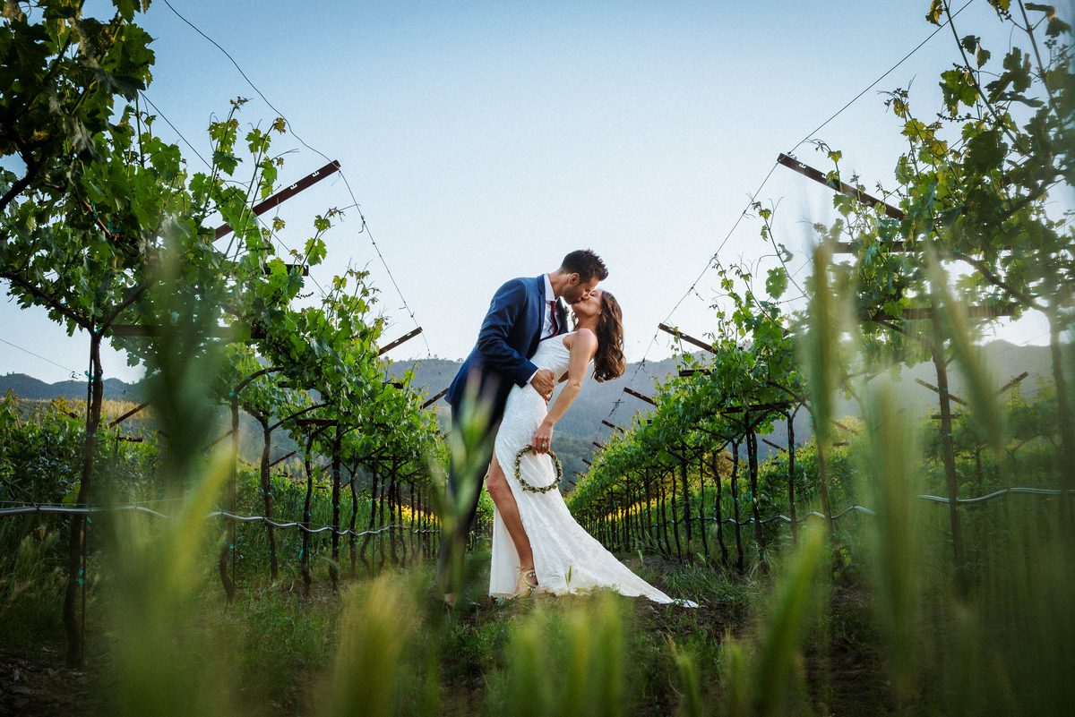 Bride and groom kissing between vineyard rows at Harvest Inn in Napa Valley