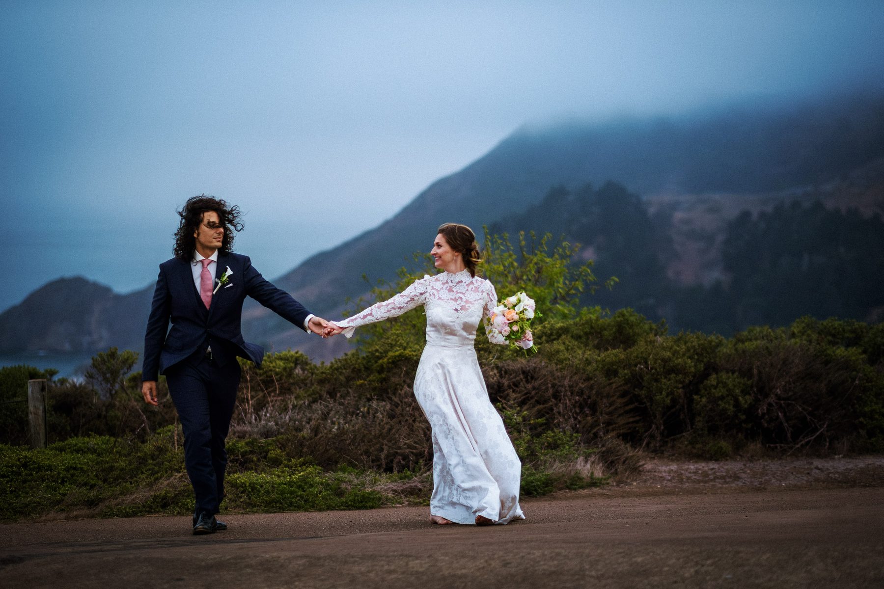 Bride and groom holding hands in the foggy Marin Headlands during their wedding portraits