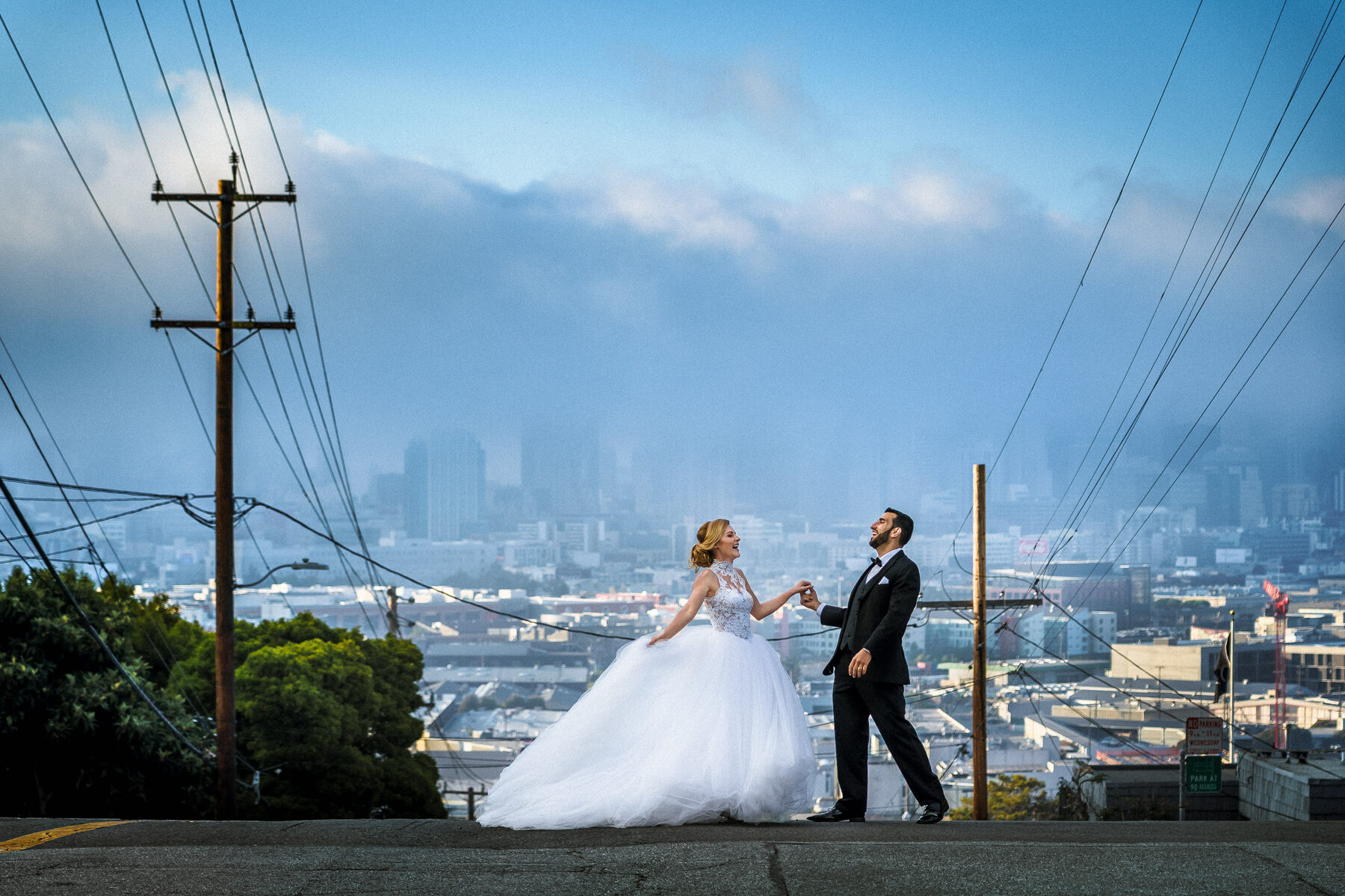 Bride and groom laughing on Potrero Hill with the San Francisco skyline behind them