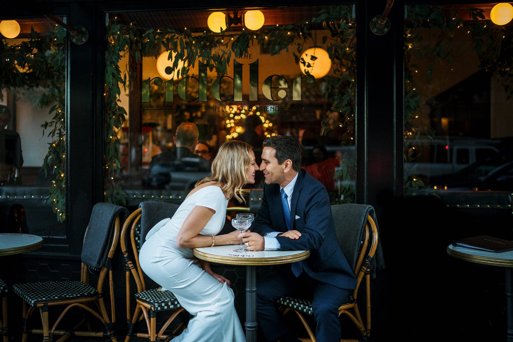 Newlyweds leaning across a sidewalk table after their San Francisco City Hall wedding